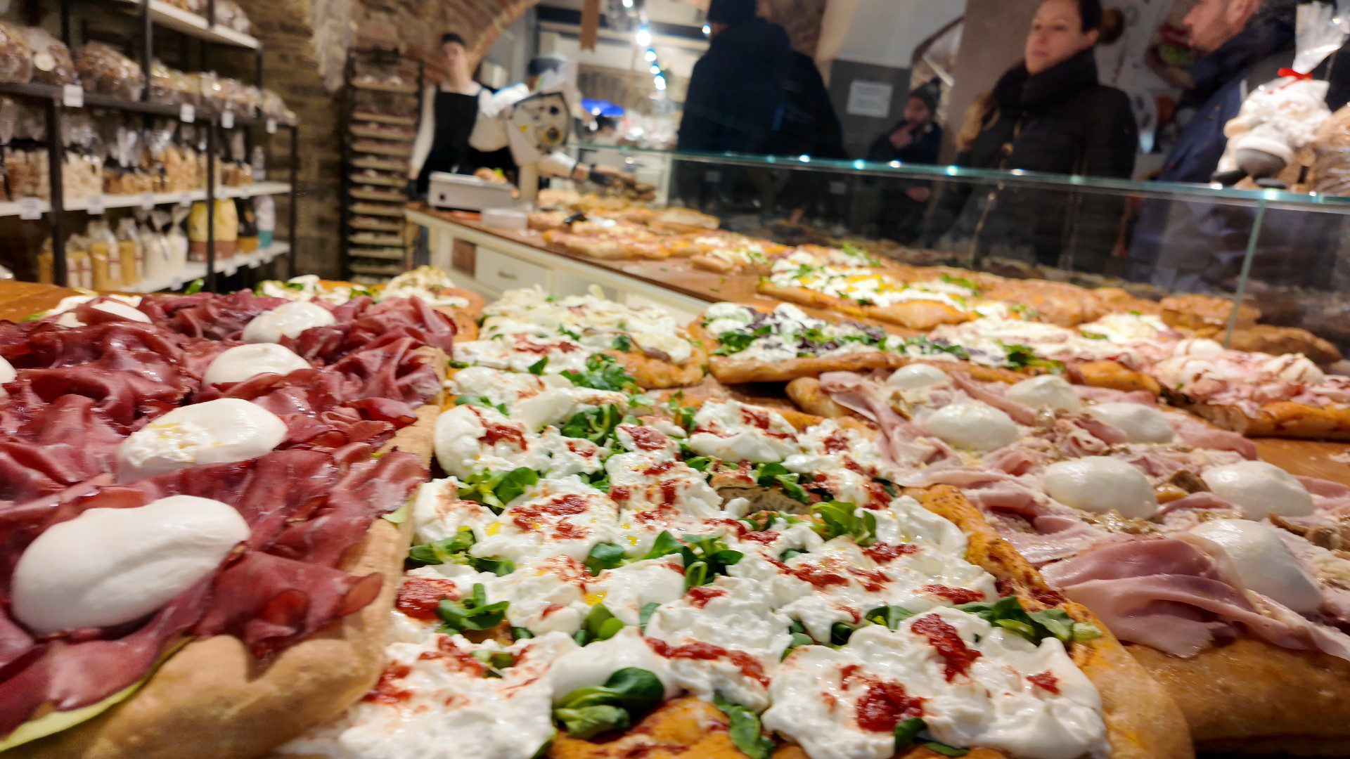 Variety of pizzas with toppings displayed.